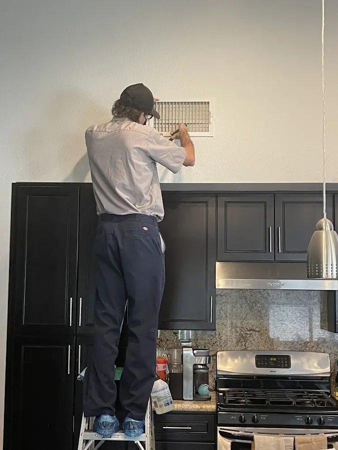 Technician inspecting an air vent during HVAC service in Wyndham